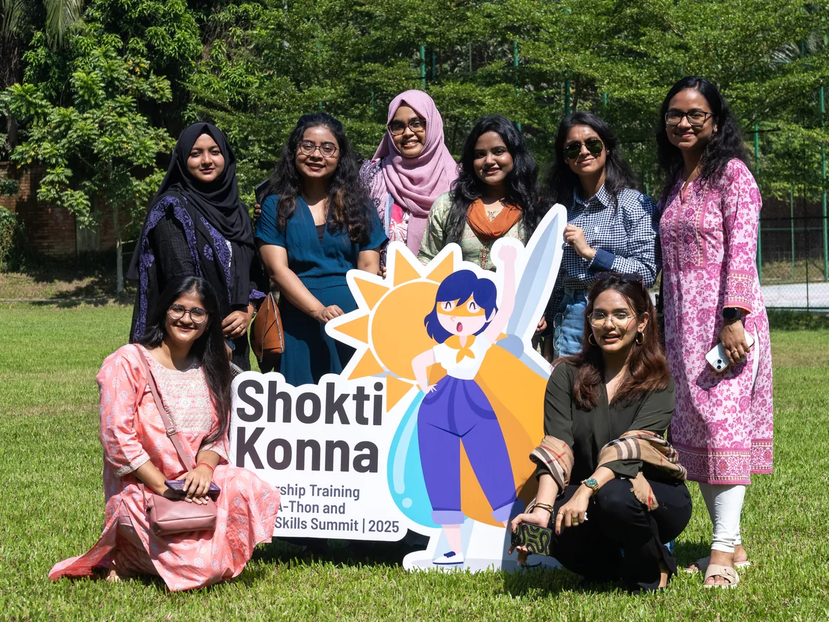 Shoktikonna participants posing with the Shoktikonna standee on a lawn during the residential bootcamp